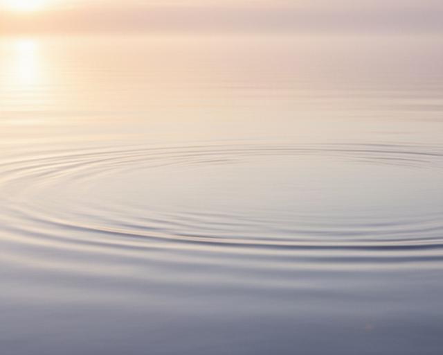 Ruhige Wasseroberfläche bei Sonnenaufgang mit klaren Linien und warmem Licht